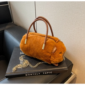 Detail of a brown faux fur cylinder handbag with leather handles and gold chain strap