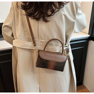 Detail of vintage crocodile texture handbag with gold hardware and snake pattern stitching