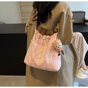Detail of pink quilted tote bag with embossed letters and cute smiley plush charm
