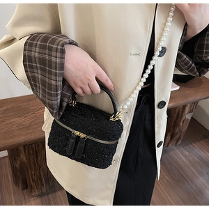 Détail du sac seau en tweed avec bandoulière en perles blanches et accents dorés
