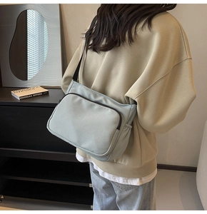 Gros plan d'un sac bandoulière en nylon vert clair montrant les poches et la texture