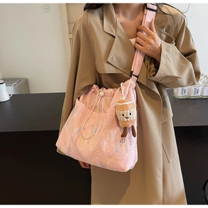 Pink quilted bucket bag with colorful embroidery and plush charm in a lifestyle setting