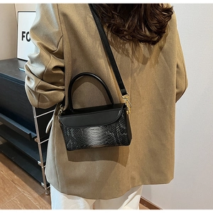 Detail of black faux python texture on handbag with gold hardware for a retro style look