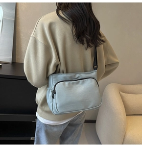 Vue latérale d'un sac bandoulière en nylon vert menthe porté par un mannequin chez soi