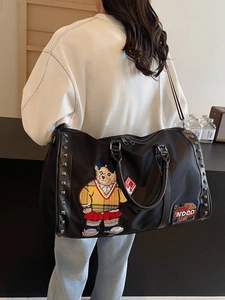 Large black travel bag with bear embroidery and rivets shown in a side lifestyle view