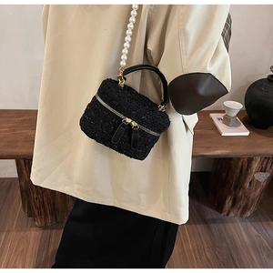 Détail du sac seau en tweed avec bandoulière en perles blanches et double zip doré
