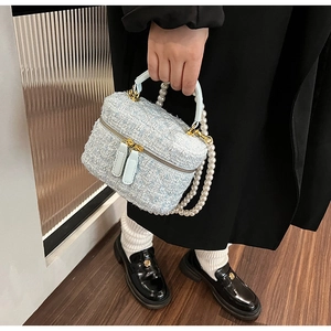 Détail du sac seau en tweed bleu clair avec bandoulière en perles et fermeture éclair dorée