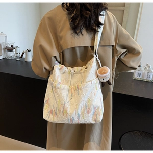 Detail of white monogram tote bag featuring colorful embroidery and cute coffee cup plush charm