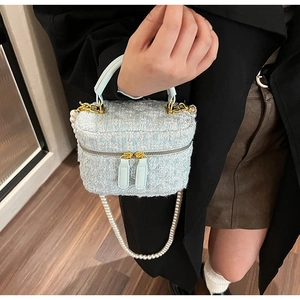 Détail du sac seau en tweed bleu clair avec bandoulière perle et dorures