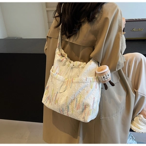 Quilted white tote bag with colorful embroidery and coffee cup charm detail
