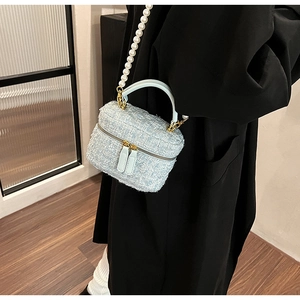Détail du sac seau en tweed bleu clair avec bandoulière perles sur manteau sombre