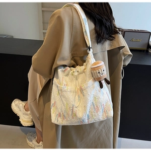 Close-up of white jacquard tote bag with colorful embroidery and coffee cup plush charm