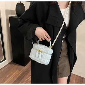 Détail du sac seau en tweed bleu clair avec bandoulière perle et texture tissée