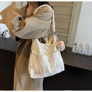 Detail of white tote bag with colorful embroidery and a cute coffee cup plush charm