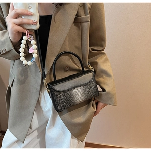 Detail of grey gradient crocodile pattern bag with gold metal hardware and leather strap