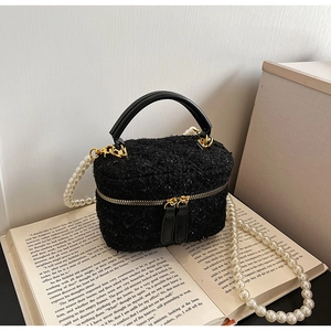 Détail de la texture en tweed noir avec paillettes et bandoulière en perles chics
