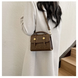 Detail view of coffee brown square bag with gold hardware stars and matte leather texture