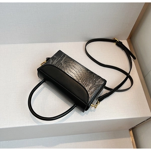 Detail of black faux snake pattern flap and golden hardware on a small crossbody bag