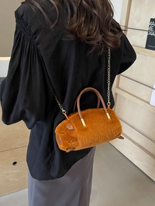 Plush brown capybara crossbody bag with gold metal chain and dual handles worn by model
