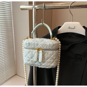 Détail du sac seau en tweed bleu clair avec bandoulière en perles et zip doré