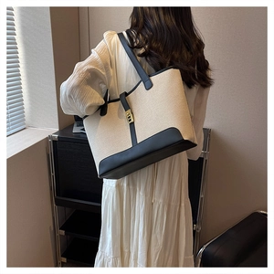 Detailed side view of canvas and leather tote bag featuring elegant gold metal clasp
