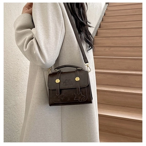 Detail of vintage brown leather crossbody bag with star embossing and gold hardware