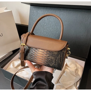Detailed view of brown snake-embossed leather handbag with gold hardware and top handle