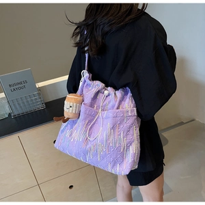 Detail of purple tote bag with diamond texture embroidery and plush coffee cup charm