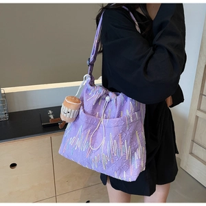 Detail of purple tote bag featuring textured fabric and colorful embroidery with plush charm