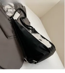 Détail de la longue bandoulière réglable et de la boucle en métal argenté du sac noir