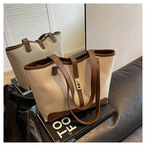 Close-up of canvas tote bag with leather trim and elegant gold metal twist lock detail