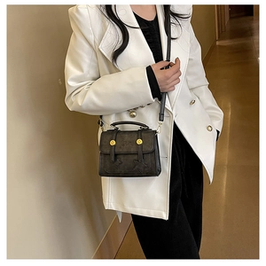 Classic black square leather bag with gold hardware worn by a model in a white blazer