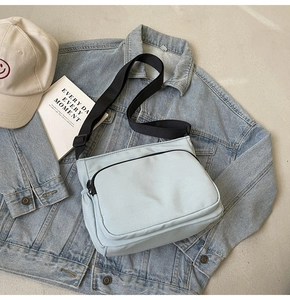 Détail d'un sac bandoulière en toile bleu clair avec sangle réglable et poche zippée