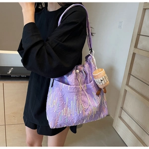Detail of purple tote bag with rainbow embroidery, drawstring top, and coffee cup charm