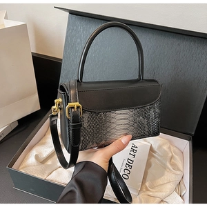 Detail of elegant black crocodile pattern handbag with gold clasp in premium gift box