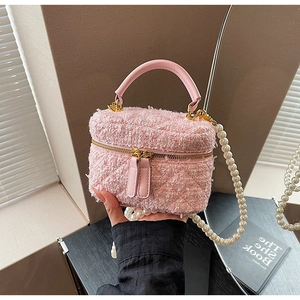 Détail du sac seau en tweed rose avec bandoulière en perles et fermetures éclair dorées