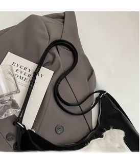 Détail du sac bandoulière noir avec broderie en polaire blanche et fermeture éclair argentée