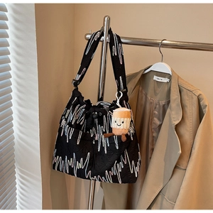 Detail of black quilted tote bag with colorful wave embroidery and plush coffee cup charm