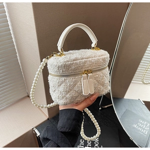 Détail du sac seau en tweed avec zip doré et bandoulière en perles chic