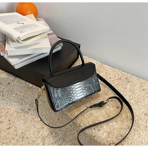 Detail of elegant black and silver snakeskin pattern shoulder bag on marble surface