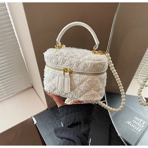 Détail du sac seau en tweed blanc avec motifs matelassés et bandoulière en perles chic