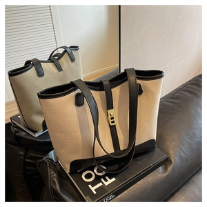 Close-up of canvas tote bags with leather trim and gold metal buckles on a sofa
