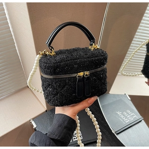 Détail du sac seau noir en bouclé avec bandoulière perles et finitions dorées