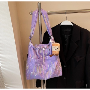 Detail of purple tote bag with textured embroidery, drawstring and plush charm