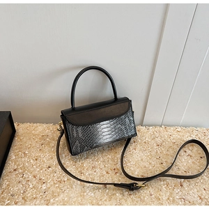 Close-up of black crocodile pattern leather handbag with gold hardware and top handle
