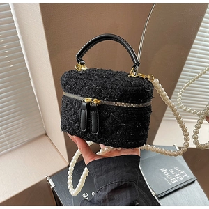 Détail du sac seau en tweed noir avec fermetures dorées et bandoulière en perles