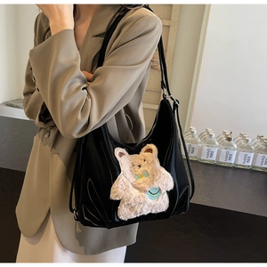 Détail d'un sac bandoulière noir brillant avec charm ours en peluche et broderie mignonne