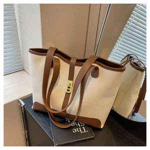 Detail of canvas tote bag with brown leather trim and golden metal clasp closure