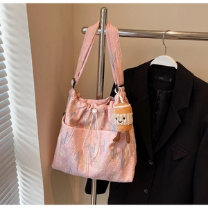 Detail view of pink tote bag featuring multi-color embroidery and plush cup charm
