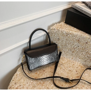 Detail of grey snake embossed texture on black tote with golden hardware and strap